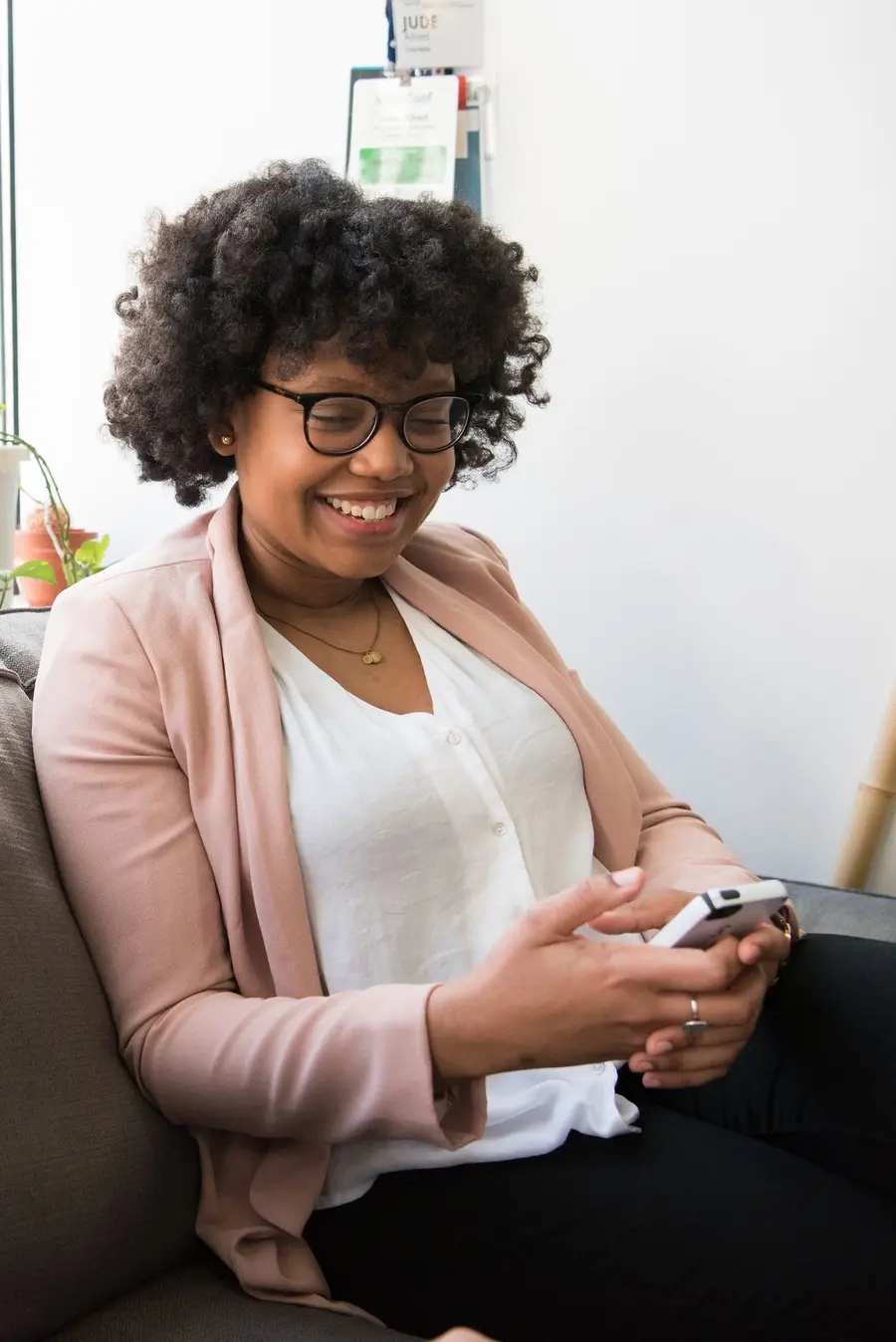 Person relaxing on a couch, smiling while using a phone